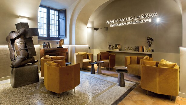 A lobby with modern furniture, a large sculpture, and a wall with 'Santa Maria La Nova' text. - La Nova Bed and Museum (Naples)
