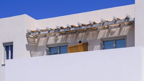 Un edificio blanco con ventanas arqueadas y un balcón con techo de tejido.
