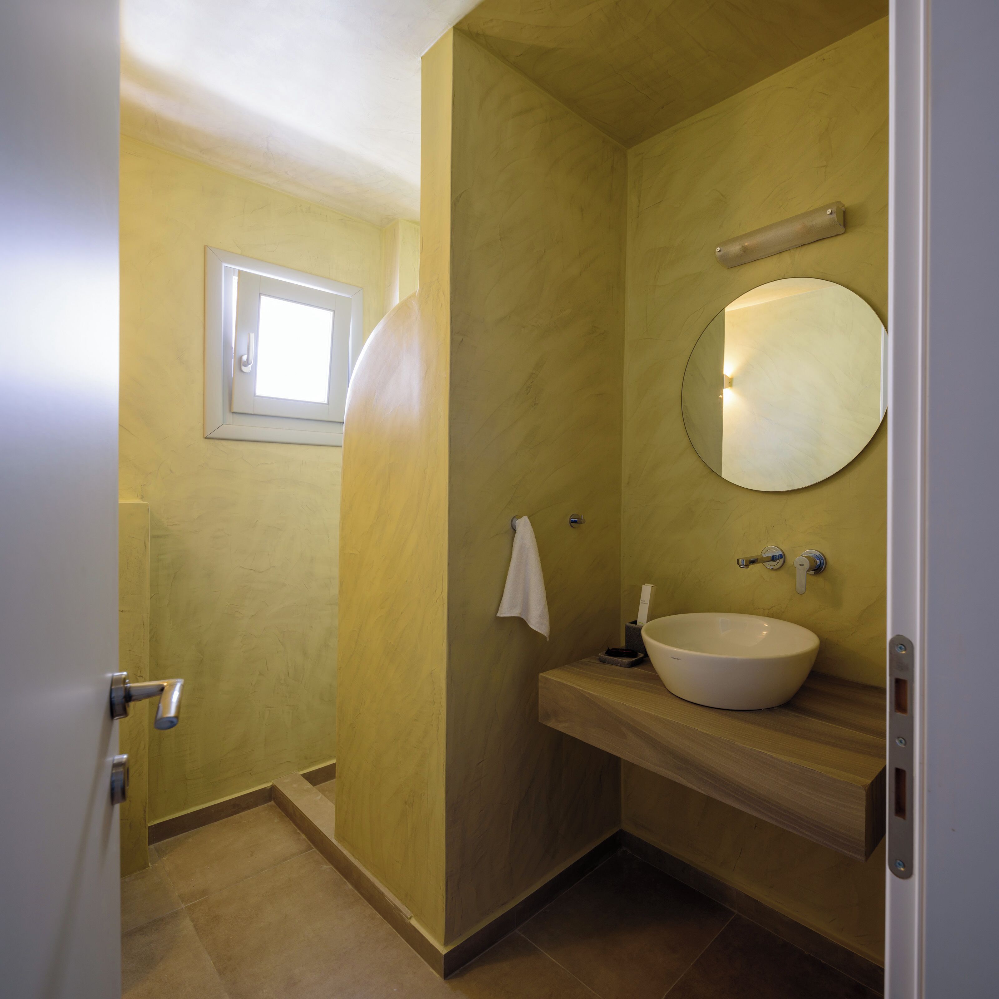 A bathroom with a large mirror, a sink, and a towel hanging on the wall.