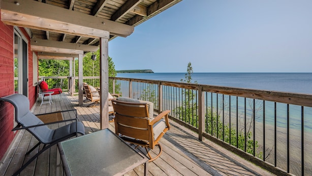 A wooden deck with outdoor furniture, a covered area, and a view of the water.