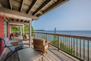 Une terrasse en bois avec des meubles d’extérieur, un espace abrité et une vue sur l’eau.