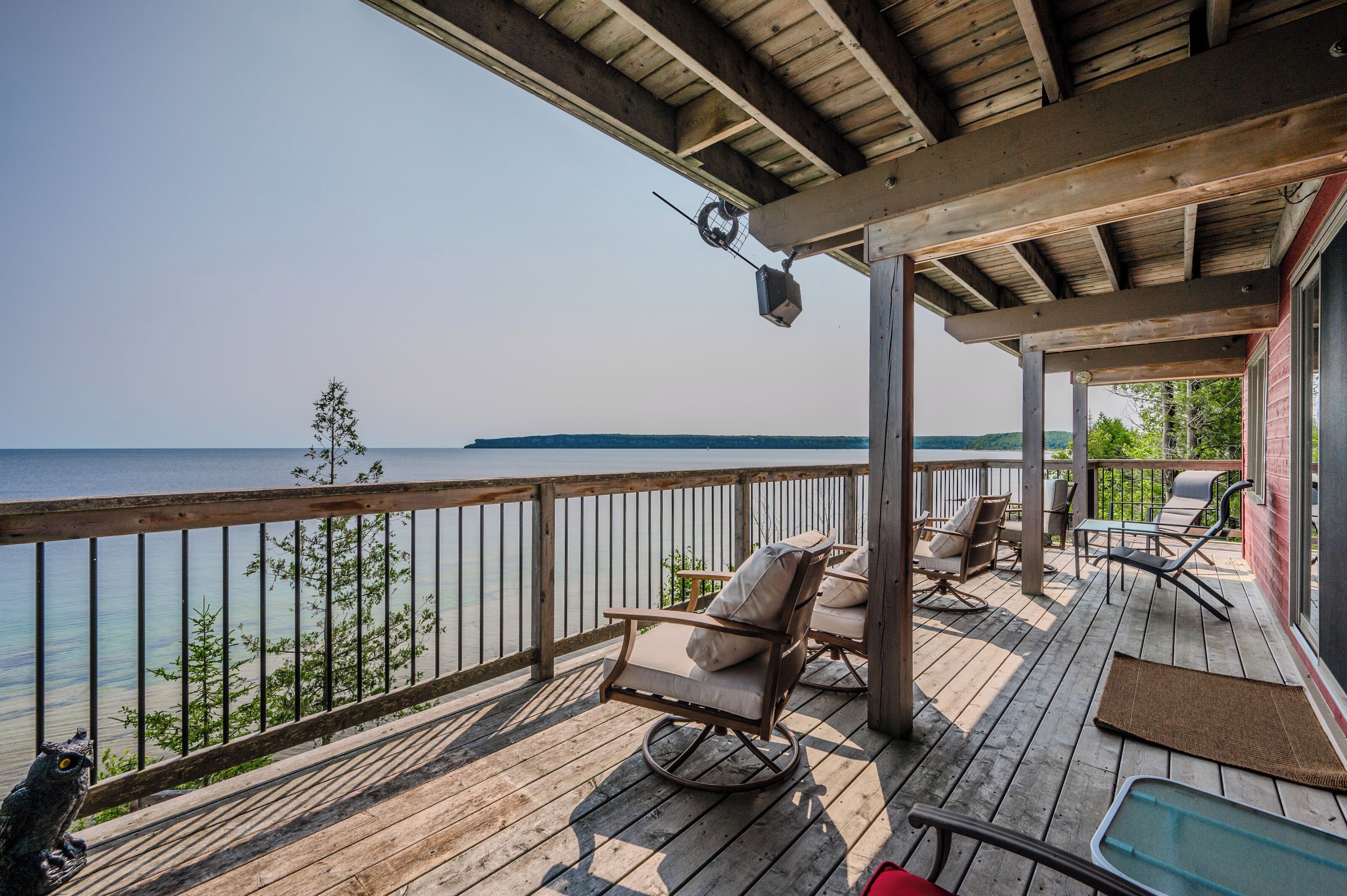 A wooden deck with a view of the water, a rocking chair, and outdoor furniture.