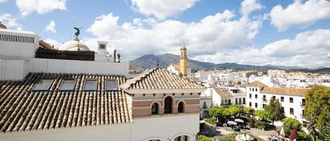 A view of a town with white buildings, a tower, and a mountain in the background.