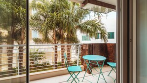 A balcony with a table and chairs, a railing, and a view of palm trees and buildings. - VL Luxury Apartment (Polignano a Mare)