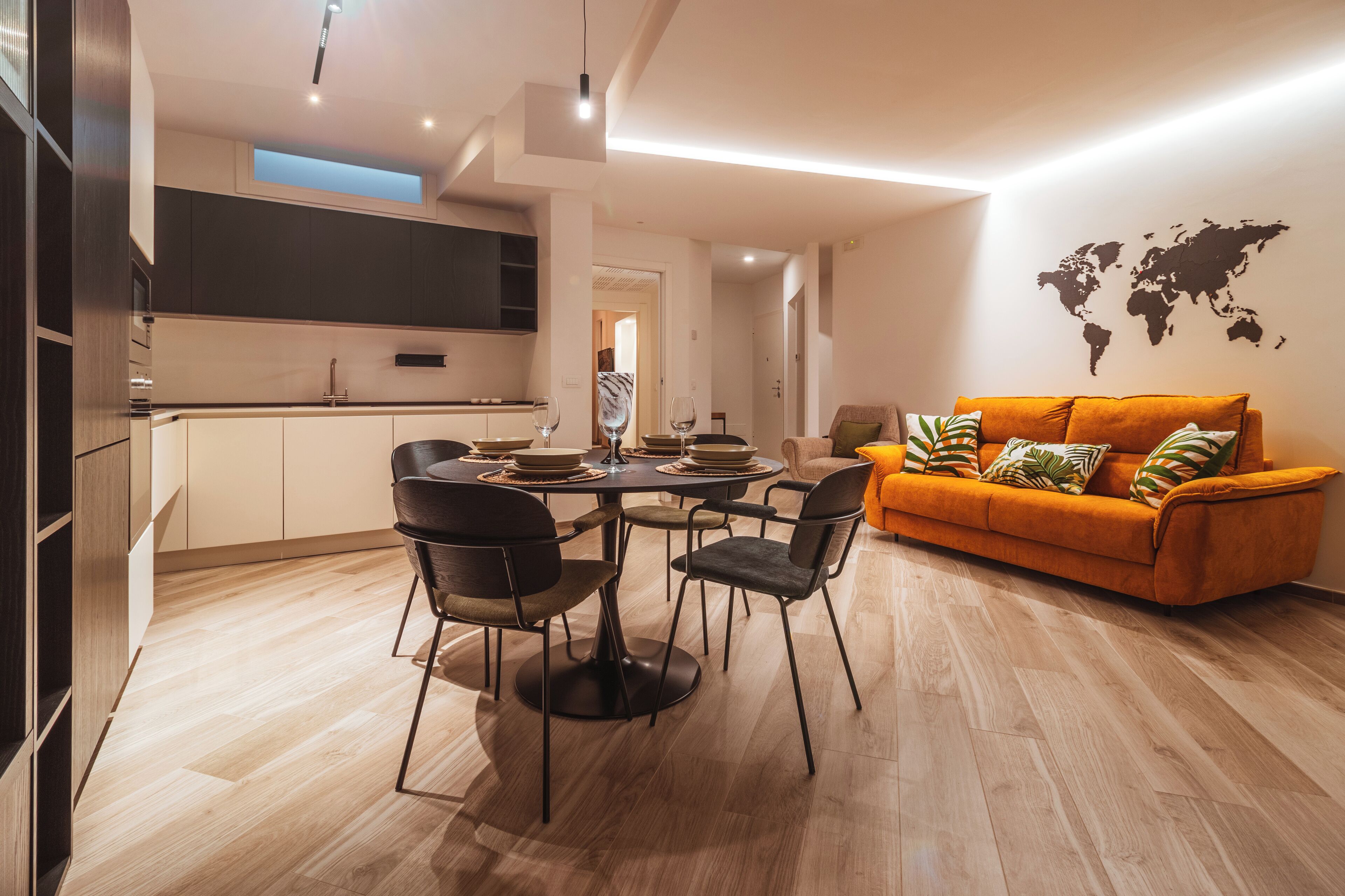 Un salon moderne avec un coin repas, comprenant un canapé, des fauteuils et une carte du monde accrochée au mur.
