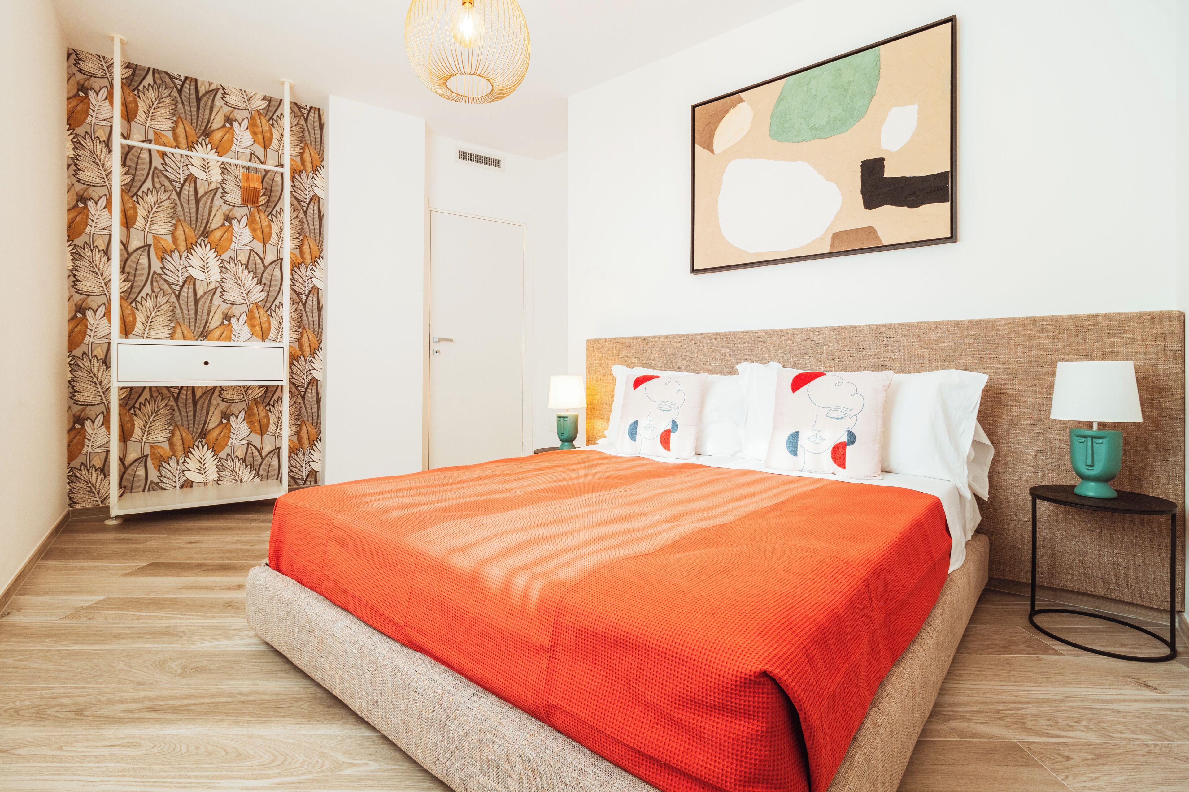 Un dormitorio con cama, armario, mesita de noche y una obra de arte en la pared.