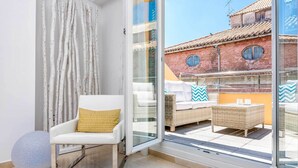 Un salon moderne avec un fauteuil blanc, un objet rond bleu et un ensemble de canapés en osier agrémenté de coussins à motifs.