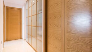 Un couloir avec une porte en bois et une porte coulissante en verre, dotée d’un cadre en bois.