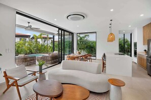 Un interior moderno con comedor, cocina y vistas al exterior.