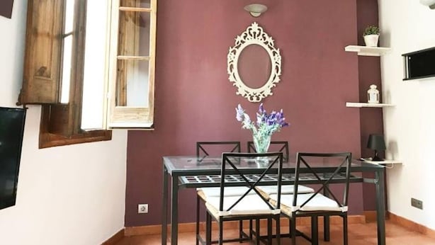 Un coin repas comprenant une table et des chaises, un miroir décoratif et une fenêtre avec un cadre en bois.