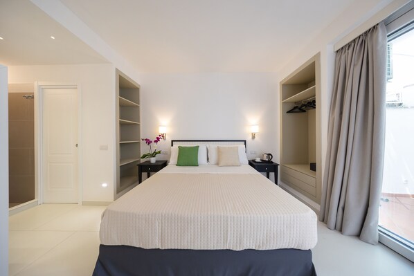 A spacious bedroom with a large bed, built-in closets, and a view through the window.