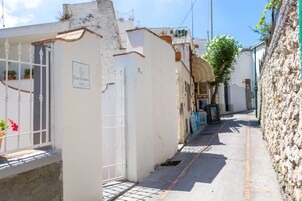 Una calle estrecha con un edificio blanco que dice "Casa Giuliani Capri".