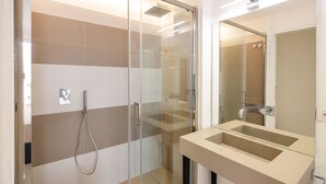 A modern bathroom with a glass shower enclosure, a beige sink with a mirror, and a visible towel rack. - Casa Giuliani Capri (Capri)