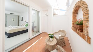 A modern room with a bed, a glass door leading to another room, wicker furniture, and a brick archway. - Casa Giuliani Capri (Capri)