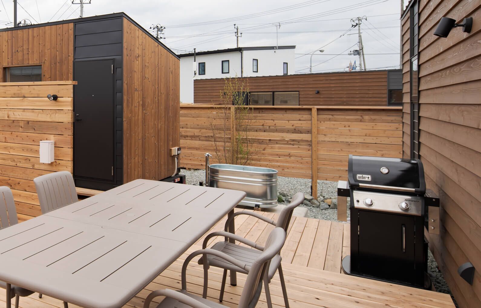 Een terras met een tafel, stoelen, een barbecue en een hottub.