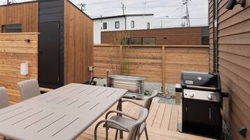 Een terras met een tafel, stoelen, een barbecue en een hottub.