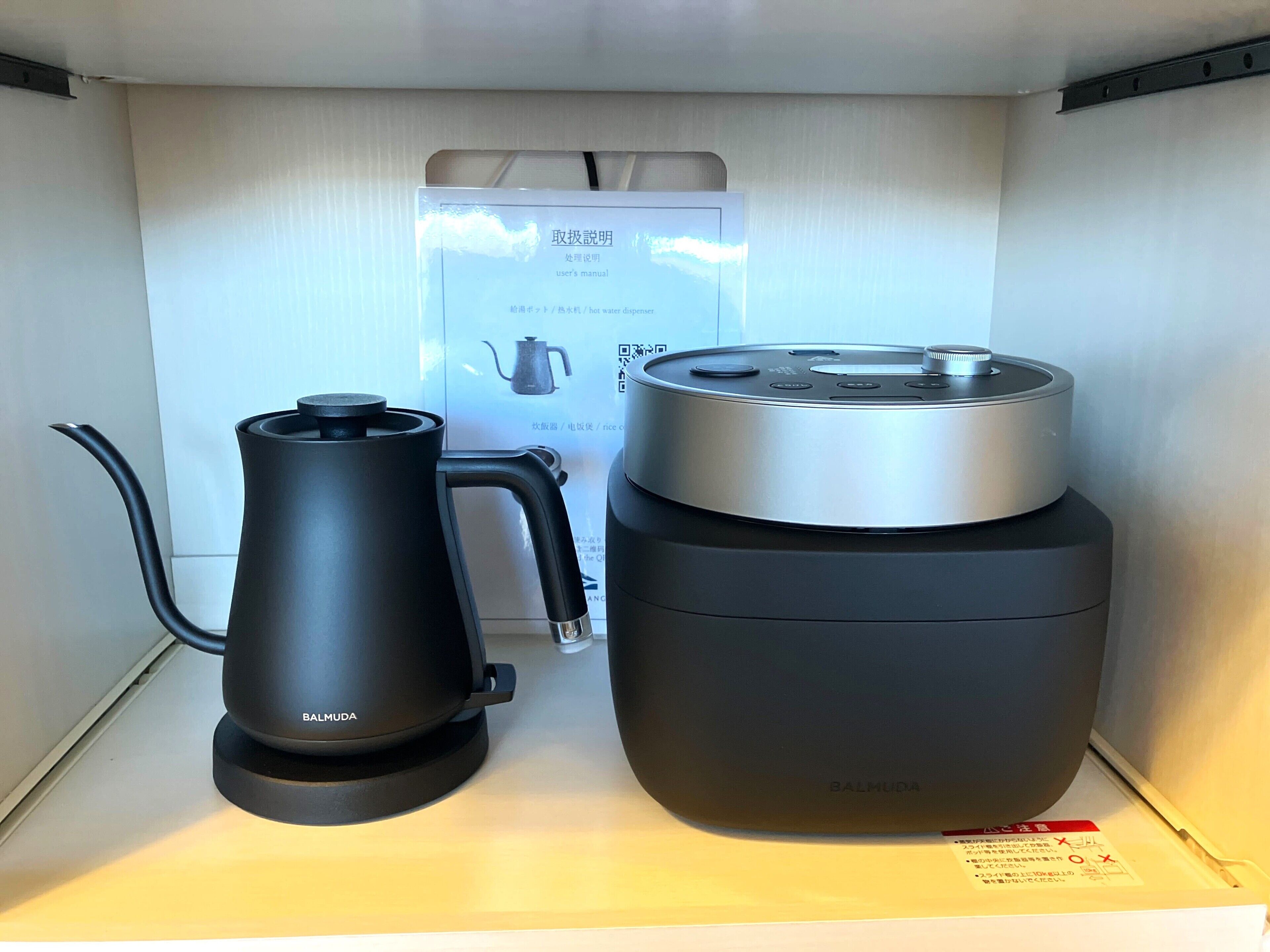 A kitchen area with a kettle and a rice cooker on a shelf.