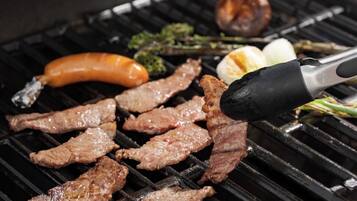 A grill with various meats and vegetables being cooked.