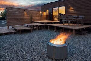 Un patio exterior con un brasero, terraza de madera y zona de estar.