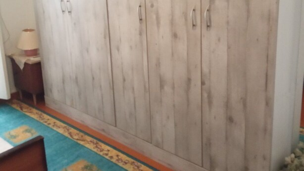 A room with a large wardrobe, a patterned carpet, and a small table with a lamp. - Blue Mansion, Plomari, Lesvos Island, Greece (Plomari)