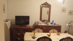 A dining area with a table set for four, a television on a cabinet, a mirror above the table, and a radiator on the wall. - Blue Mansion, Plomari, Lesvos Island, Greece (Plomari)