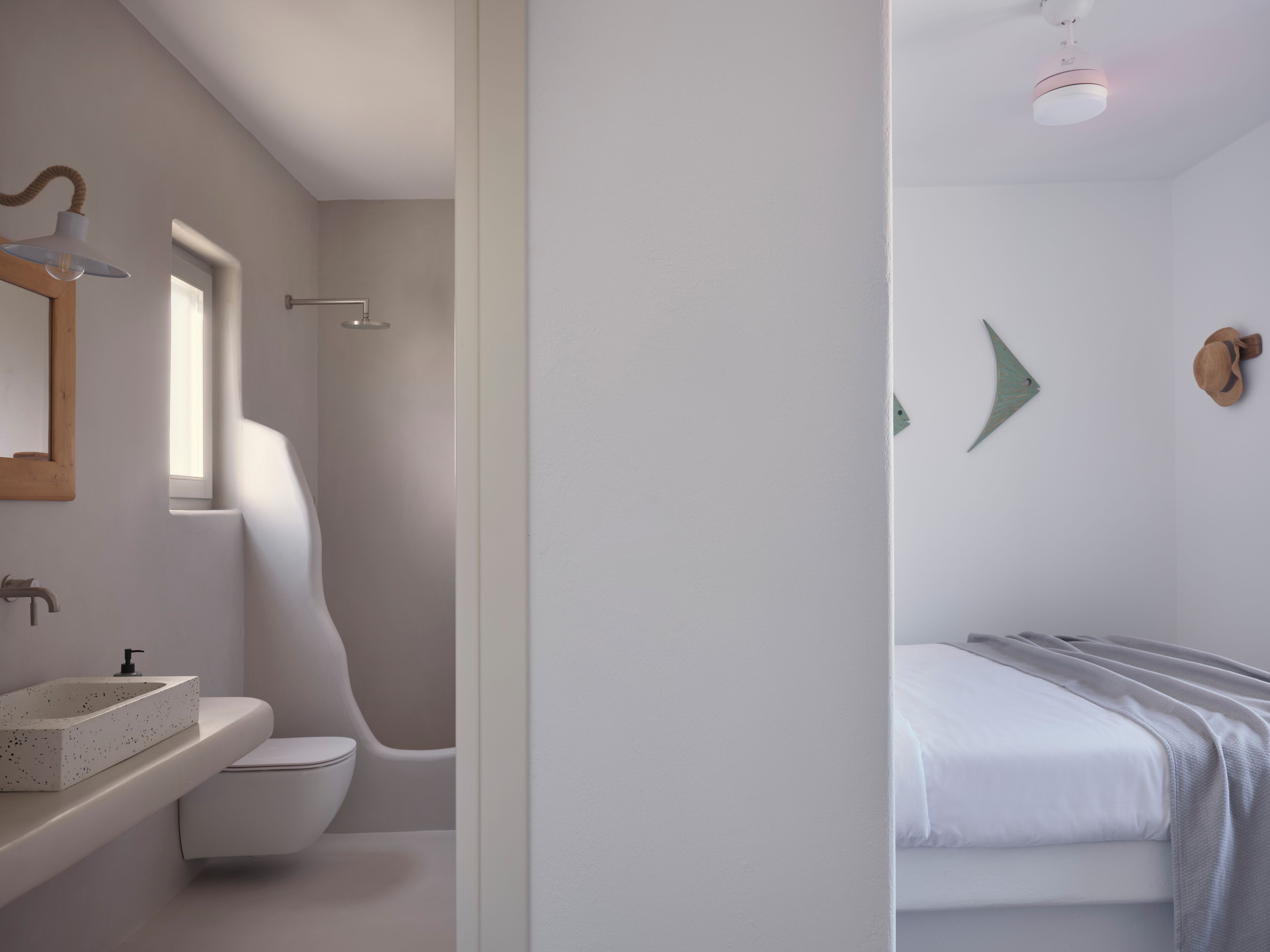 Un bagno moderno con lavabo curvo, servizi igienici e doccia. Sopra il lavabo c'è uno specchio e una luce a soffitto.