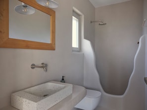 Une salle de bain moderne avec une baignoire sur pieds, un lavabo rectangulaire doté d’un plan de toilette à motifs, et un miroir à cadre en bois avec trois lampes.