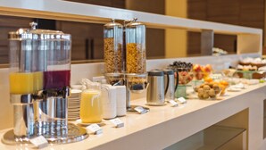 A buffet setup with various food and drink dispensers, including a coffee maker and a fruit bowl. - Pride Elite Phaltan (Phaltan)