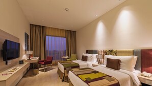 A hotel room with two beds, a TV, a desk, and a chair. - Pride Elite Phaltan (Phaltan)