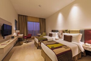 Una habitación de hotel con dos camas, televisión, escritorio y una silla.