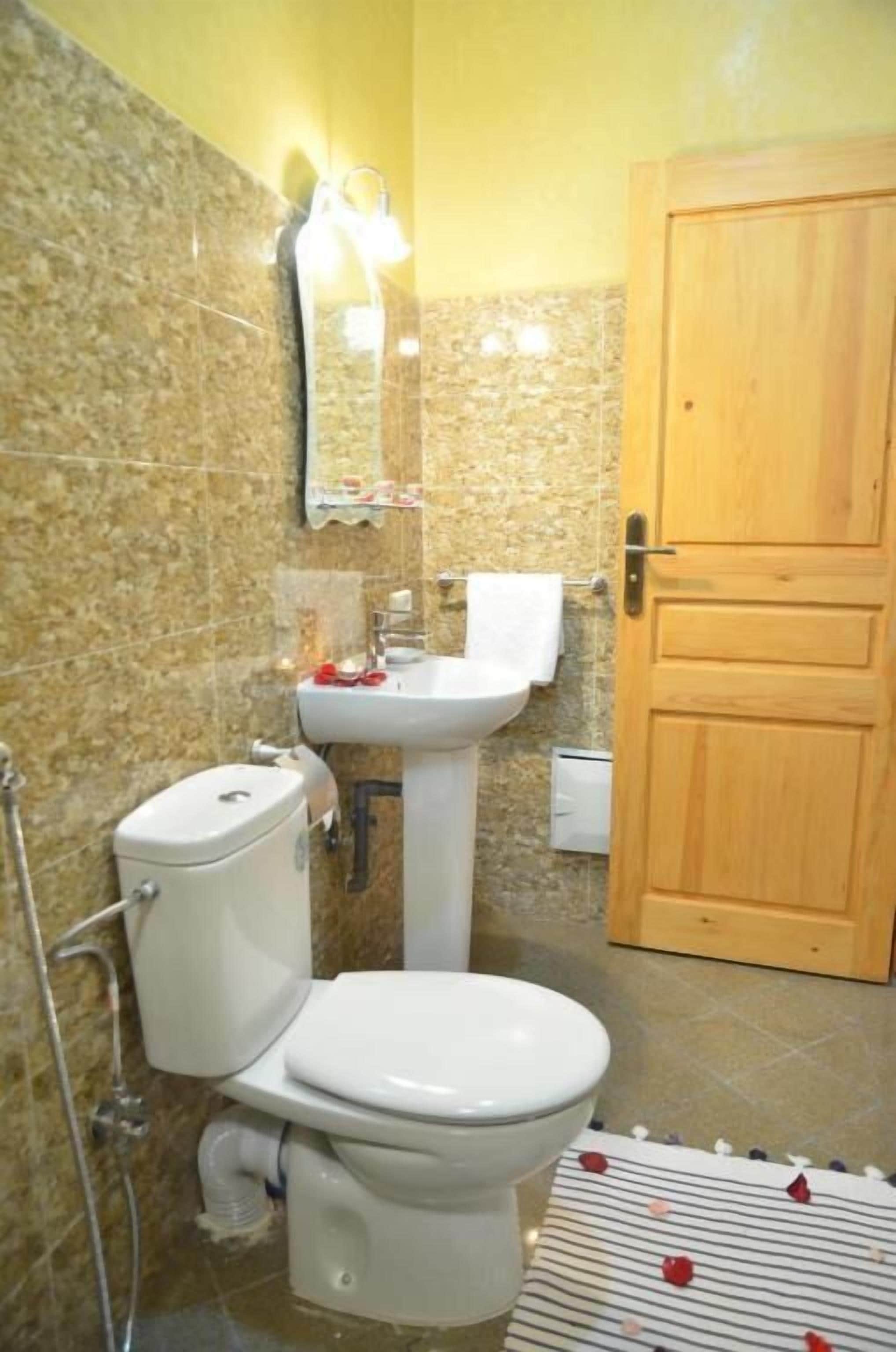 A bathroom with a toilet, sink, and mirror.