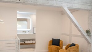 A modern living room with two mustard-colored armchairs, a white radiator, and a wooden floor.
