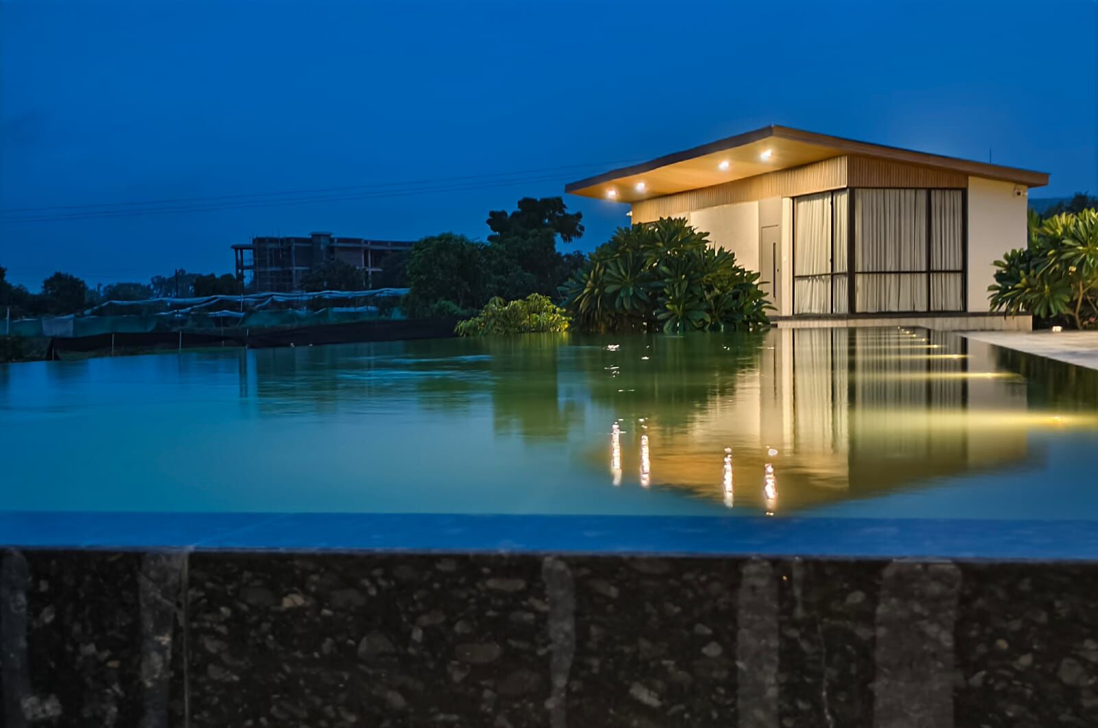 Un edificio moderno con una piscina in primo piano, immerso nel verde.