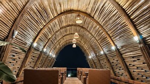 An arched wooden ceiling with seating and hanging lights. - River's Edge By Escape Stays (Nashik)