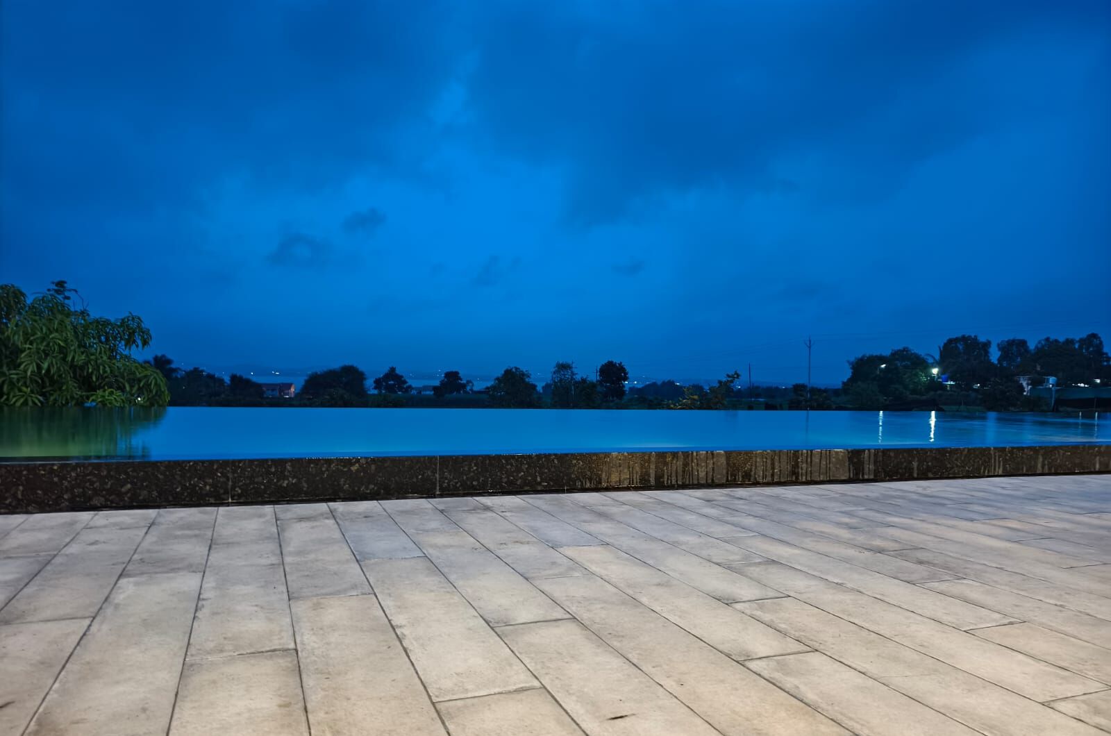 A waterfront terrace with a view of the water and distant trees.
