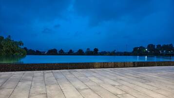 A waterfront terrace with a view of the water and distant trees.