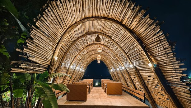 A bamboo arch structure with seating and a hanging light fixture. - River's Edge By Escape Stays (Nashik)
