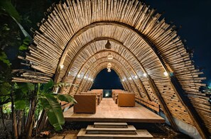 A bamboo arch structure with seating and a hanging light fixture. - River's Edge By Escape Stays (Nashik)