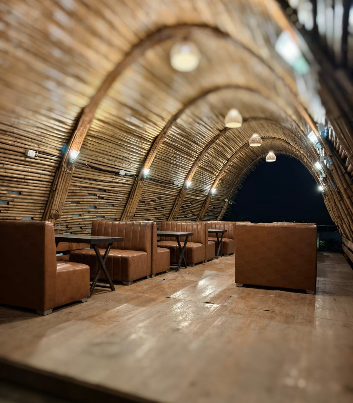 Un interior con techo de madera curva, asientos de cuero y mesas.