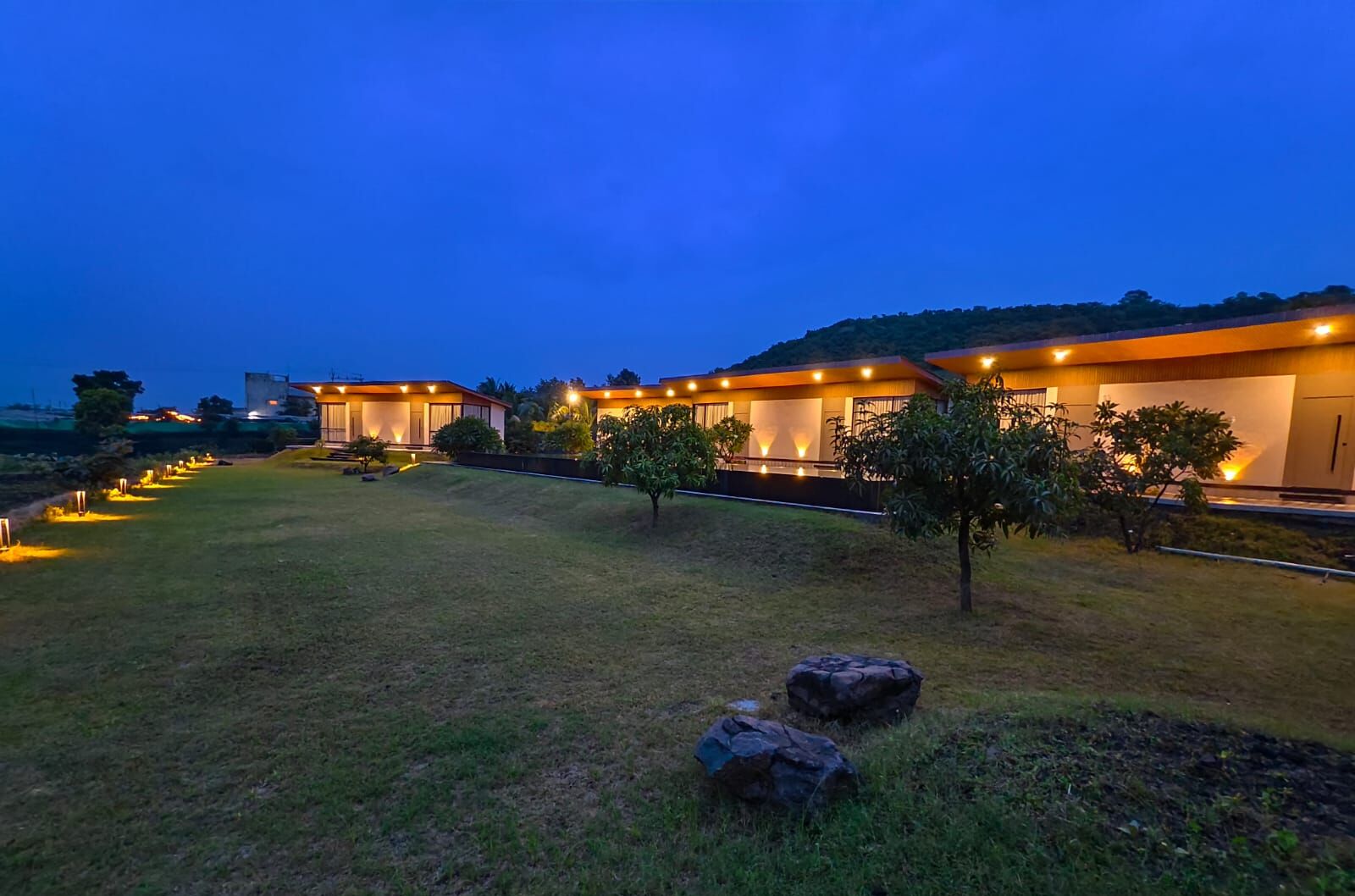 A modern hotel with a well-lit lawn and a clear view of the surrounding landscape.