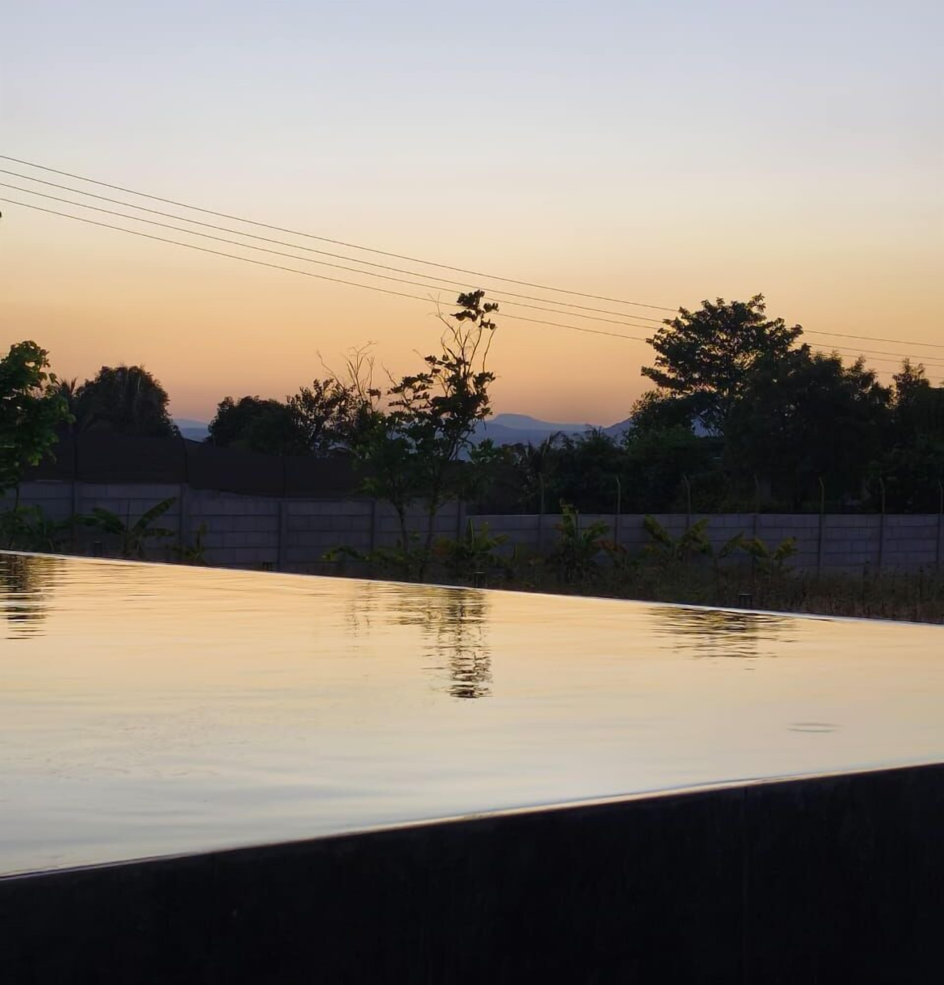 Una piscina con vista a árboles y una cordillera distante.