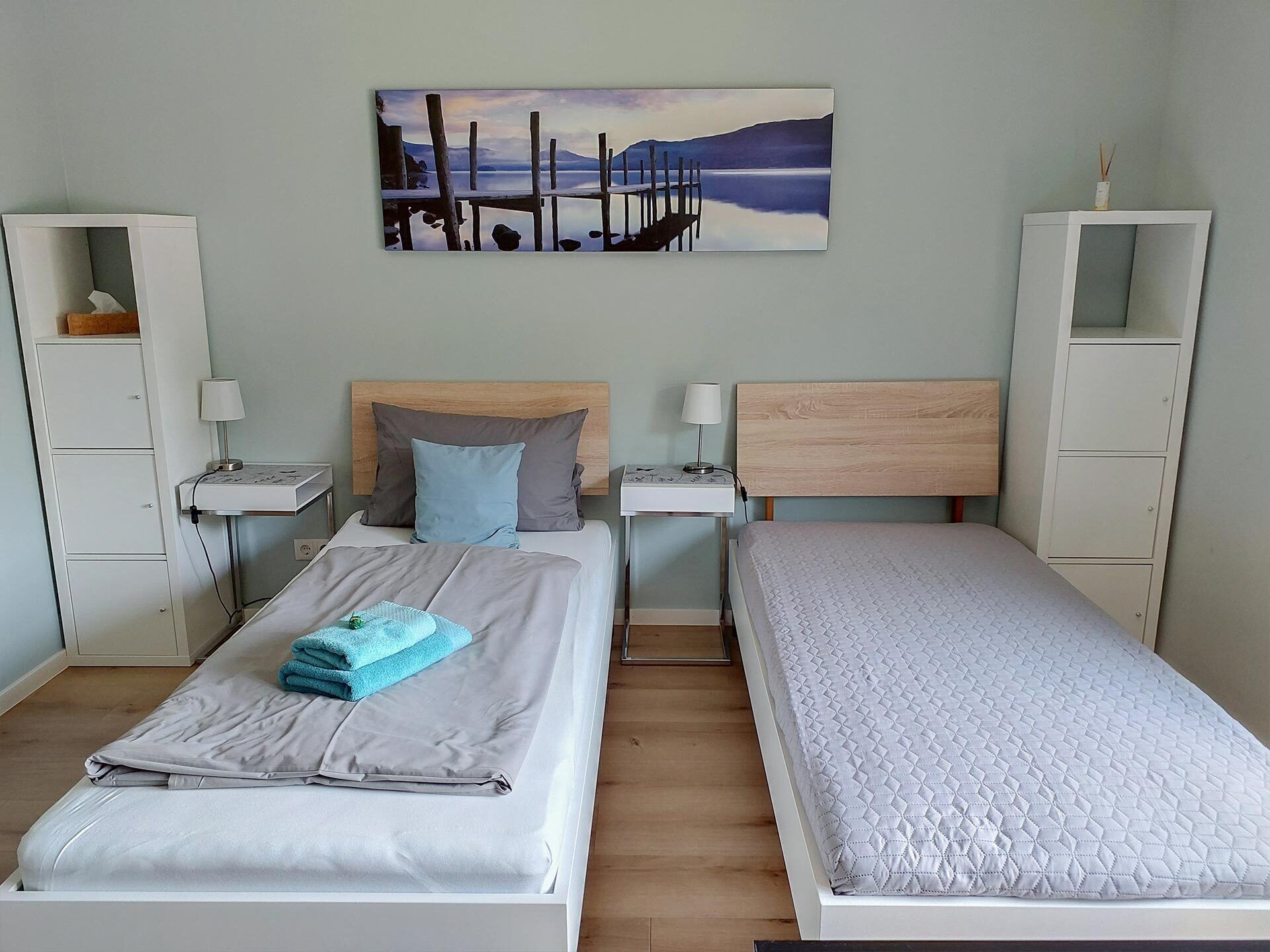 Ein Schlafzimmer mit zwei Betten, einem Nachttisch mit Lampe, einem Beistelltisch und einem Bild an der Wand.