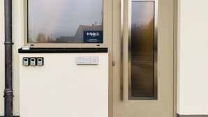 A beige door with a glass panel, a small window above the door, and a number '65' on the wall. - triple a Apartments in Altfeld (Marktheidenfeld)