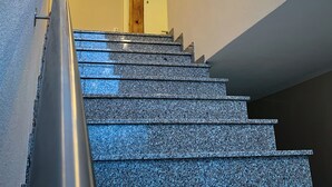 A staircase with a wooden handrail and a light fixture above. - triple a Apartments in Altfeld (Marktheidenfeld)
