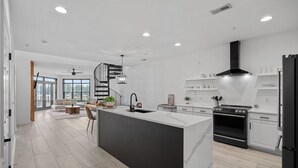 Cozinha moderna com ilha central, forno embutido e armários brancos.