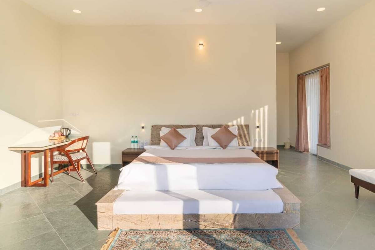 A bedroom with a large bed, a bedside table, a chair, and a small table with items on it.