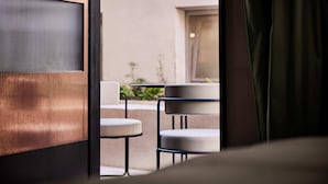 A modern hotel room with a view of an outdoor seating area, a large window, and a curtain. - Boutique Hotel Badhaus (Bressanone)