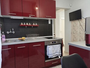 A modern kitchen with red cabinets, a stainless steel sink, and a built-in oven. - NDK Top Center Sofia Two Bedroom Apartment with ACC (Sofia)