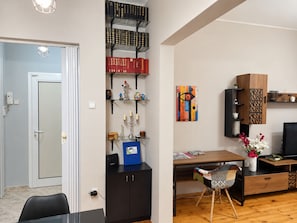 A modern living room with a dining area, featuring a bookshelf, artwork, and a television. - NDK Top Center Sofia Two Bedroom Apartment with ACC (Sofia)