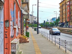 Vista de una calle con acera, un automóvil estacionado y edificios de fachadas coloridas.